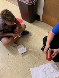 two boys work on a mock up of a wind turbine