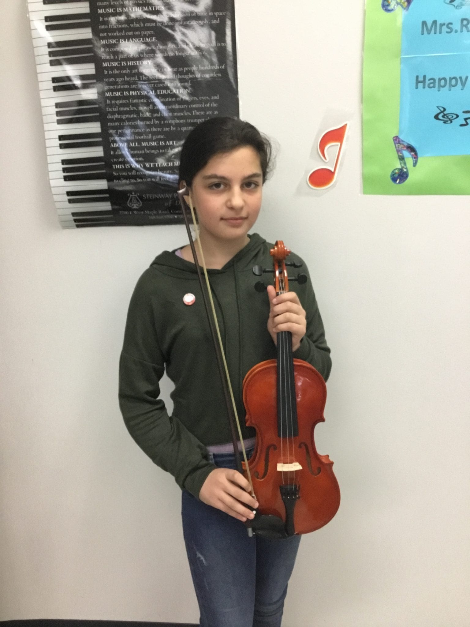 A Becker student poses with her violin while proudly wearing her newly awarded Intermediate Pin.