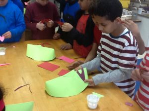 Students are cutting and gluing the lips to their paper mask