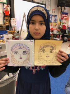 A fourth grader showing her self-portrait on paper and foam plate