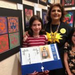 Sarah M. with her family infront of her artwork