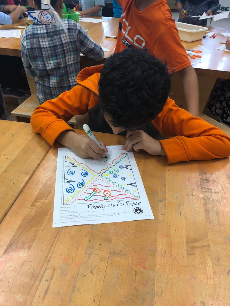 a student working on adding lines and colors to the last triangle of his pinwheel