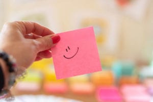 Smily face on pink post it.
