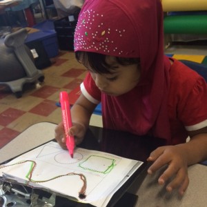 This student has the work brought closer to her on a slant board and traces pre-writing shapes, an important skill needed before a child can trace/write letters.