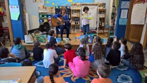 Teacher with guitar on stage with a student. 