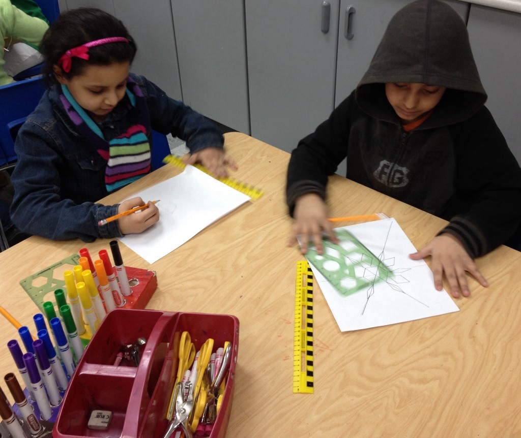 Using a geometric stencil and a ruler, second graders begin creating a radial design.
