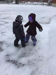 A boy and a girl outside standing on ice.