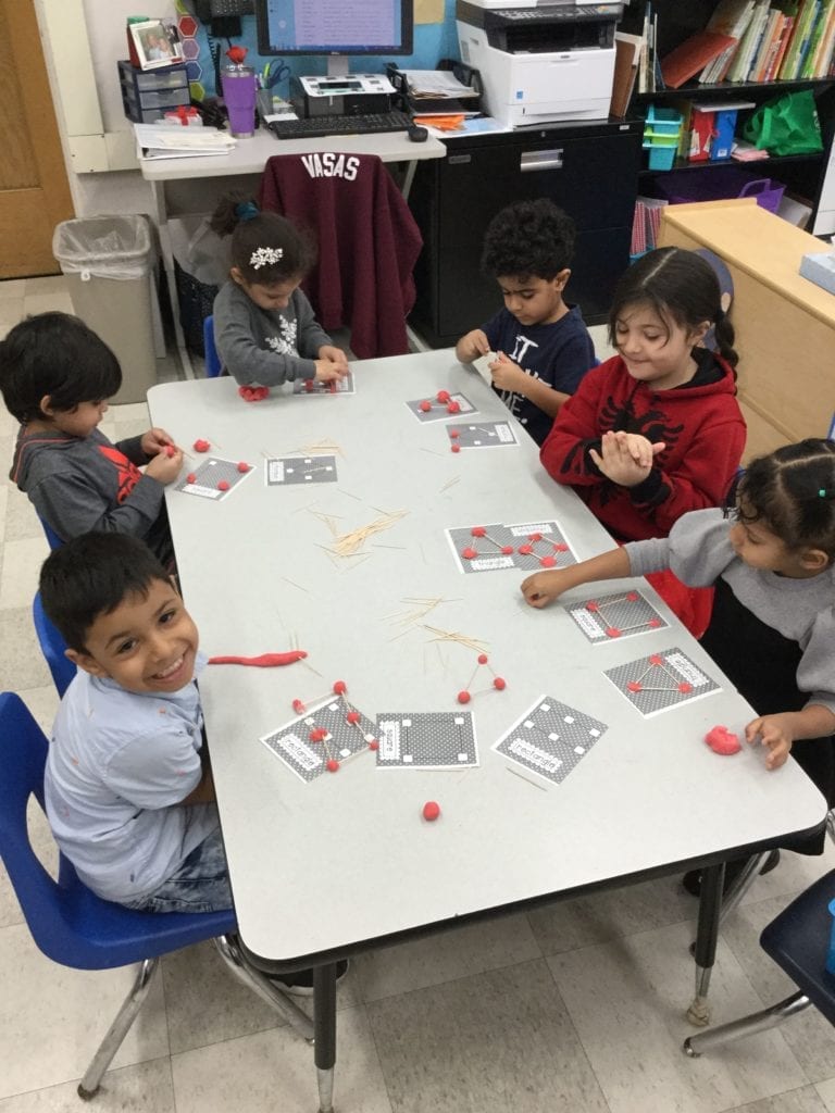 6 children sitting at a table creating with playdough and toothpicks.